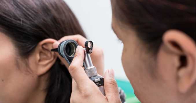 Audiologist performing ear inspection prior to hearing assessment at Hear in Texas