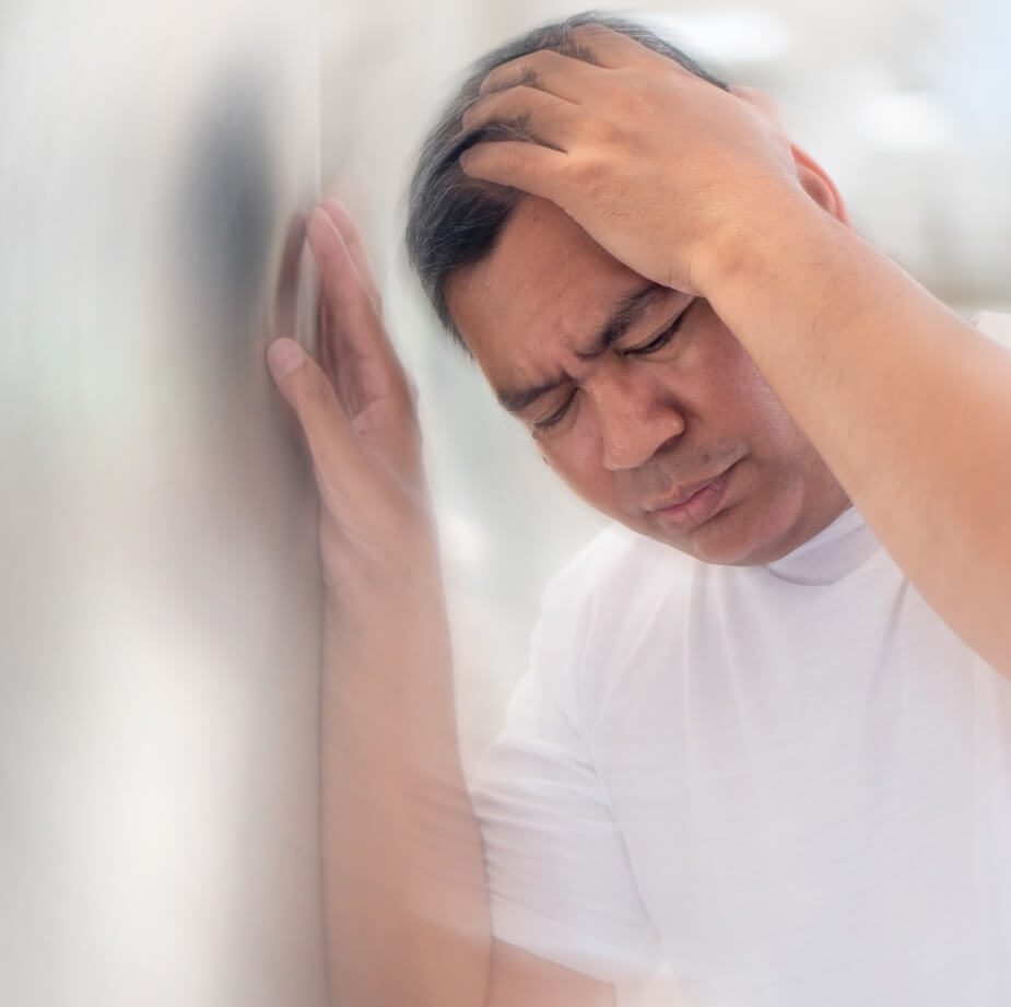 Man suffering from dizziness holding against a wall