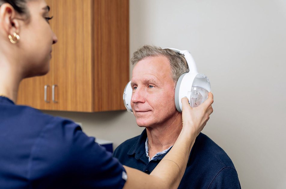 Audiologist performing earwax removal using earigator