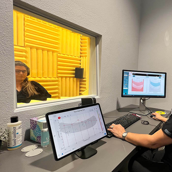 A female having her hearing tested in a sound booth at Hear in Texas